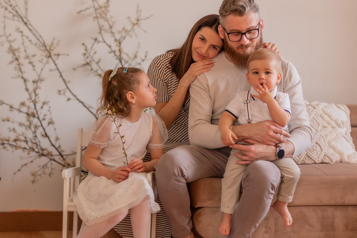 Rodzina siedząca razem na kanapie – mama, tata, córka i synek