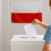 Dziecko wrzuca kartkę do urny wyborczej na tle polskiej flagi – symbol przyszłości i znaczenia głosu.