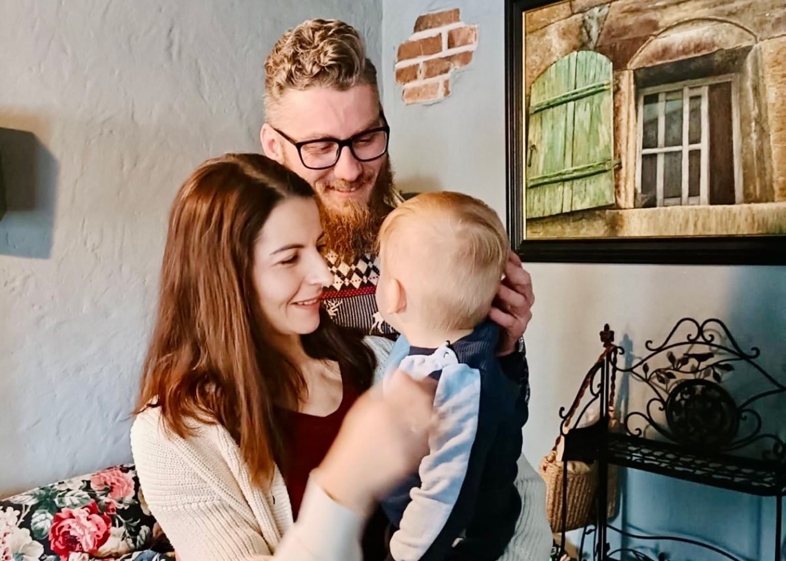 Mama i tata przytulają małego chłopca podczas pierwszego spotkania adopcyjnego